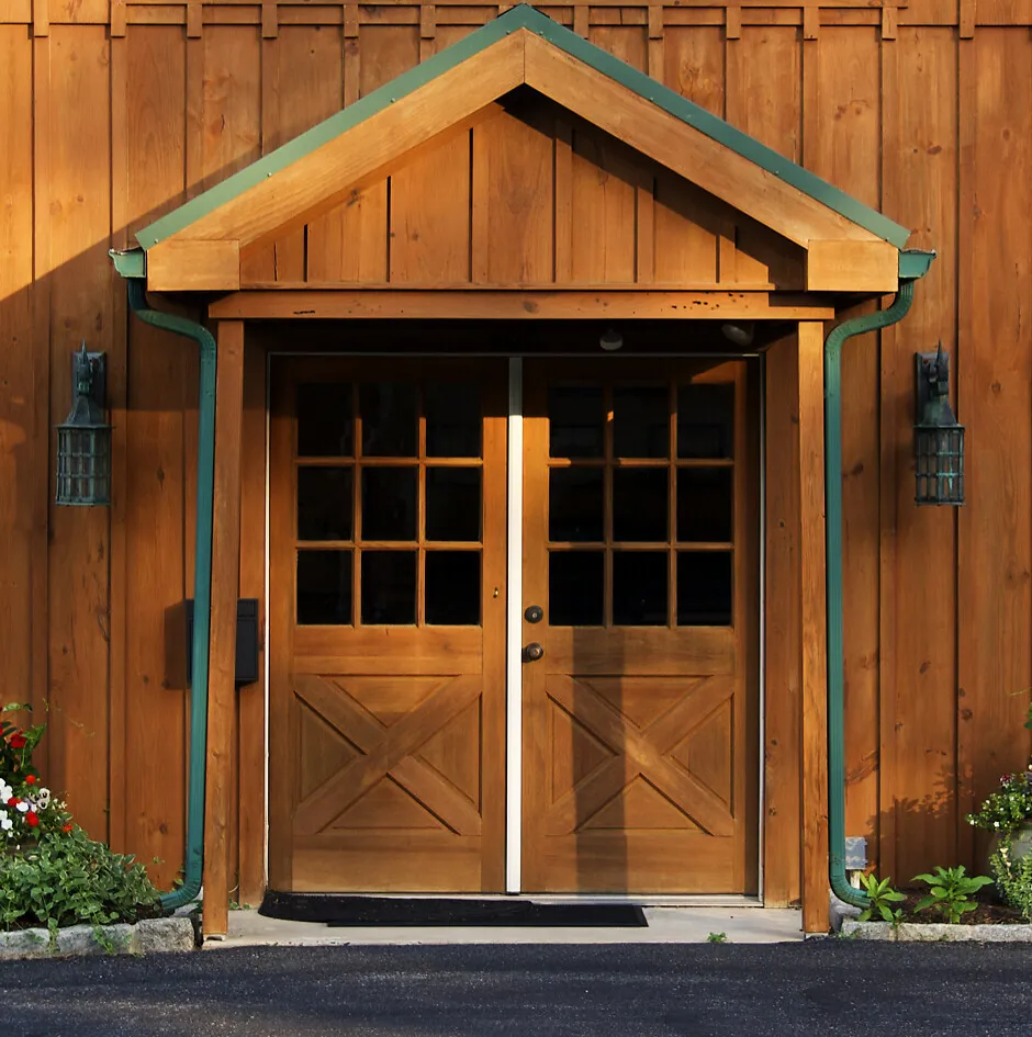 The double-door entrance to the Southeastern Executive Health office in Chadds Ford: wooden doors under a peaked portico with green trim, flanked by two lantern sconces