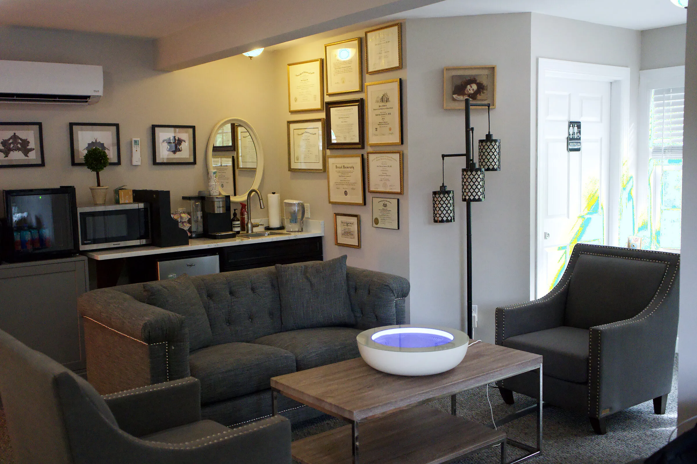 The warm, unhurried sitting room at the Chadds Ford office, with soft seating, a gallery wall, and a coffee station